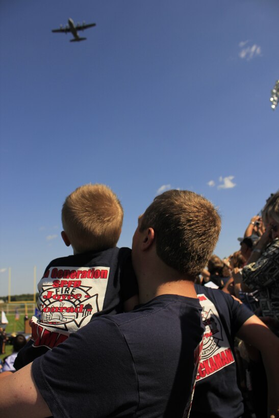 Thomas Heckaman III and IV, husband and son of St. Paul firefighter Kathryn Heckaman, watch a 934th Airlift Wing C-130 flyover at Coon Rapids high school tribute to the heroes of 9/11.  (Air Force Photo/Master Sgt. Nicolette Shegstad)