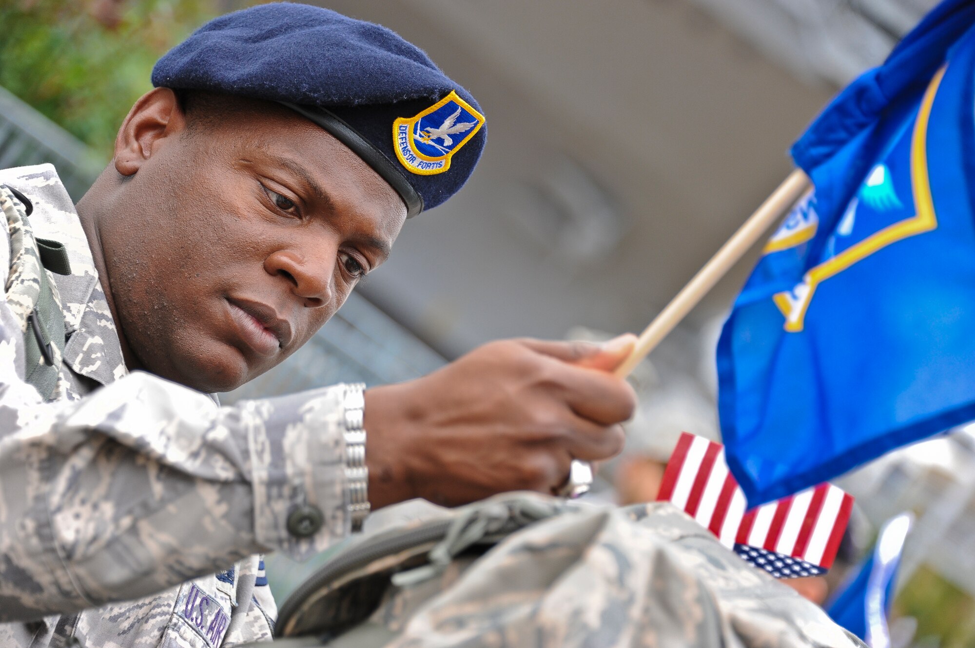 A Joint Base McGuire-Dix-Lakehurst security forces member helps a fellow ruck marcher with attaching the Defensive Fortis flag to his ruck sack. The security forces members marched from the Intrepid Sea, Air and Space Museum in New York City Sept. 11 to Battery Park, where 2,796 flags covered the area to honor each person who died on 9/11. They were cheered on by the New York community as they marched along the shoreline. (U.S. Air Force photo by Airman 1st Class Dennis Sloan/Released)