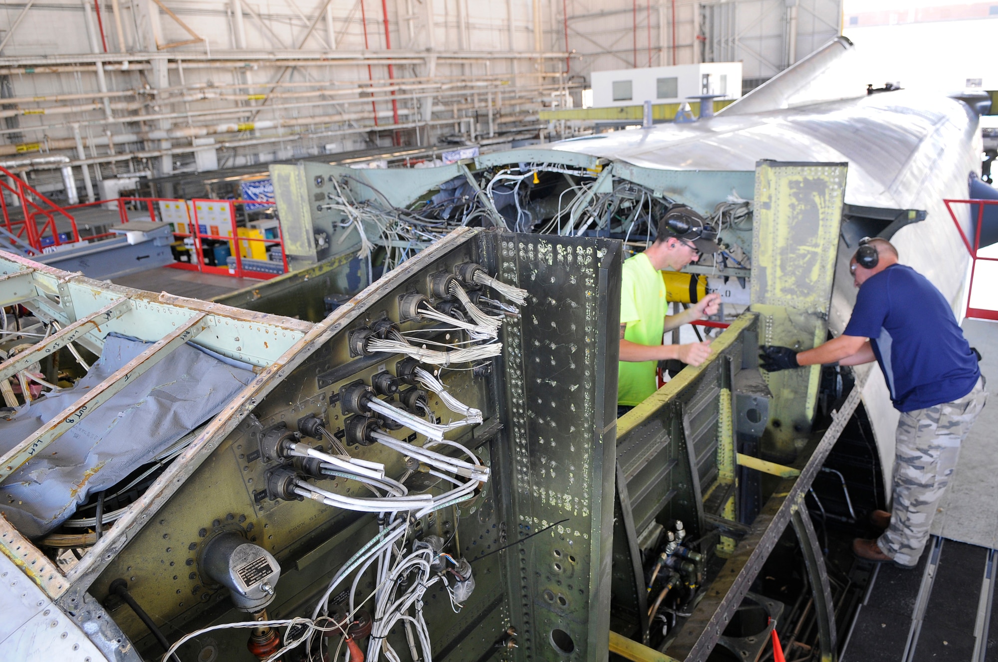 Matt Wynne and Chris Grimsley, sheet metal mechanics, remove beams on a C-130 to prepare it for a new center wing box. U. S. Air Force photo by Sue Sapp