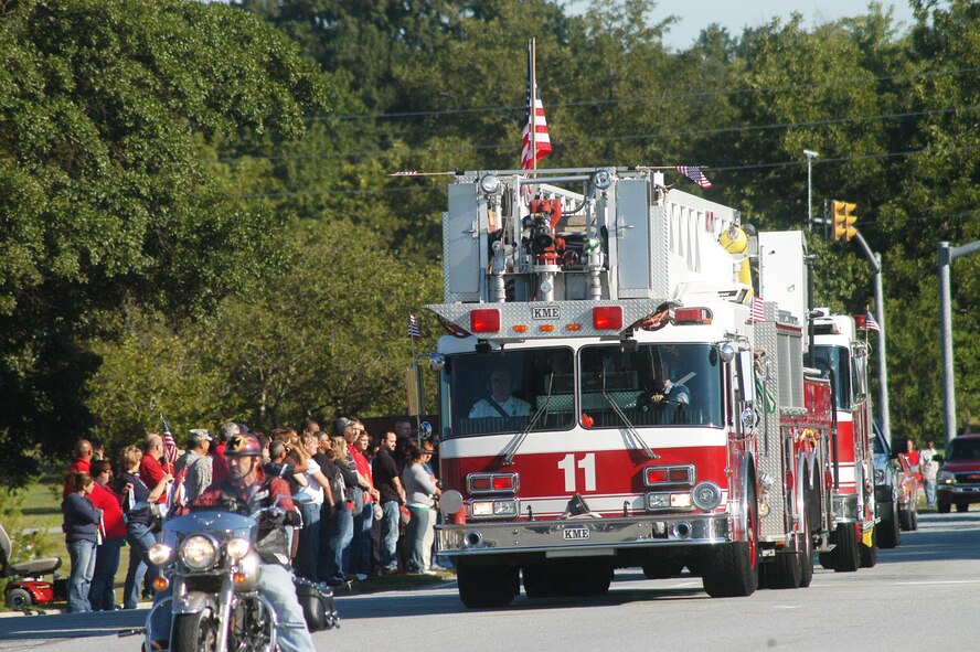 Team Robins members show respect as a Robins fire truck carrying an artifact stone from the Sept. 11 Pentagon attack passes on Robins Parkway. The processsion began on Richard Ray Boulevard and travelled to the Museum of Aviation. U. S. Air Force photo by Sue Sapp