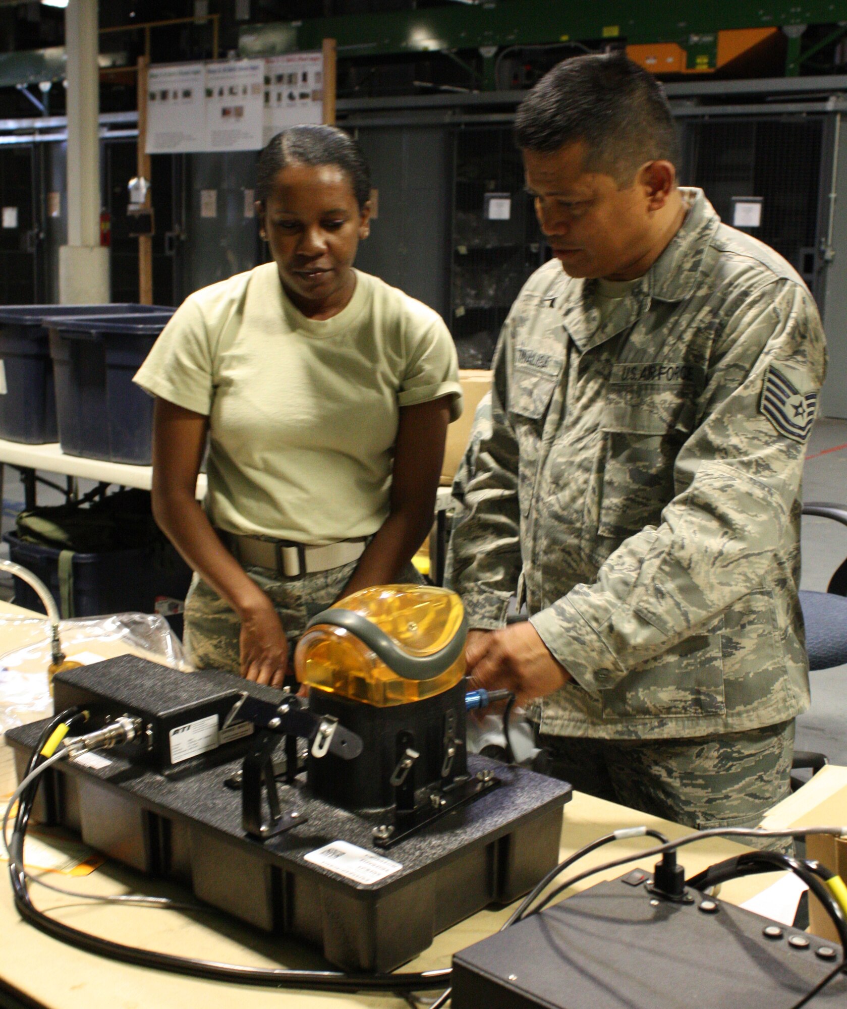TRAVIS AIR FORCE BASE, Calif. -- Tech. Sergeant Bernardo Tinaliga, 349th Logistics Readiness Squadron, trains Airman 1st Class Alivia Hampton, 349 LRS, on how to properly test gas masks during a routine leakage test here on August 5, 2011. (U.S. Air Force photo by Senior Airman Amelia Leonard)
