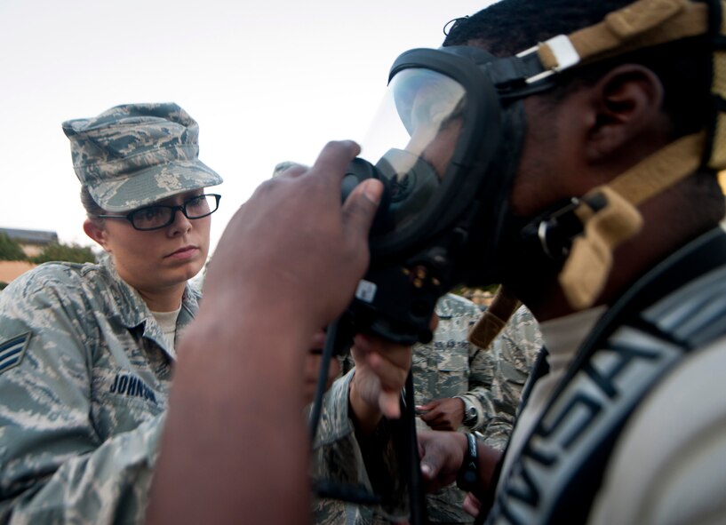 U.S. Air Force Senior Airman Amanda Johnson, 23rd a Aerospace Medical Squadron bioenvironmental engineering technician, helps an Airmen adjusts his gas mask while preparing for a training exercise at Moody Air Force Base, Ga., Sept. 14, 2011. Airmen in hazardous chemical environments are required to wear a protective suit, nitrile gloves and rubber boots to prevent contamination to any of the hazardous chemicals in the environment. (U.S. Air Force photo by Airman 1st Class Joshua Green)
