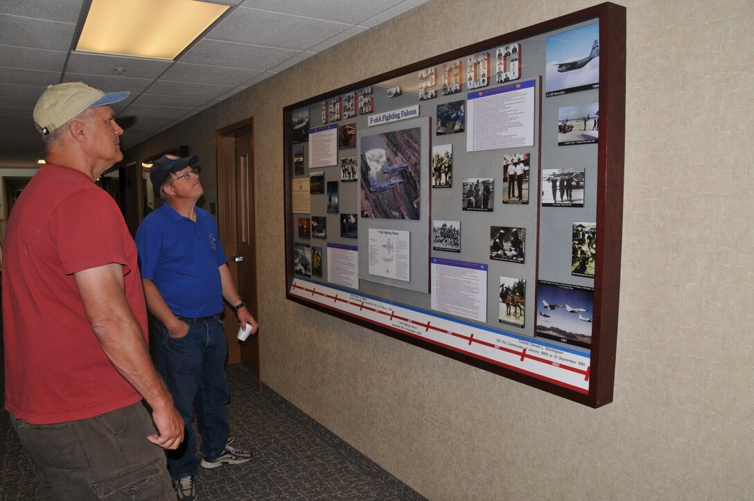 Retired Chief Master Sgt. Dana Darko and retired Senior Master Sgt. Mark Giskass view one of the four encased photomontages highlighting the major missions, aircraft and personnel assigned to the 120th Fighter Wing which were recently placed on the wall of the newly remodeled Headquarters Building on July 20, 2011.
 (U.S. Air Force photo by Senior Master Sgt. Eric Peterson.)