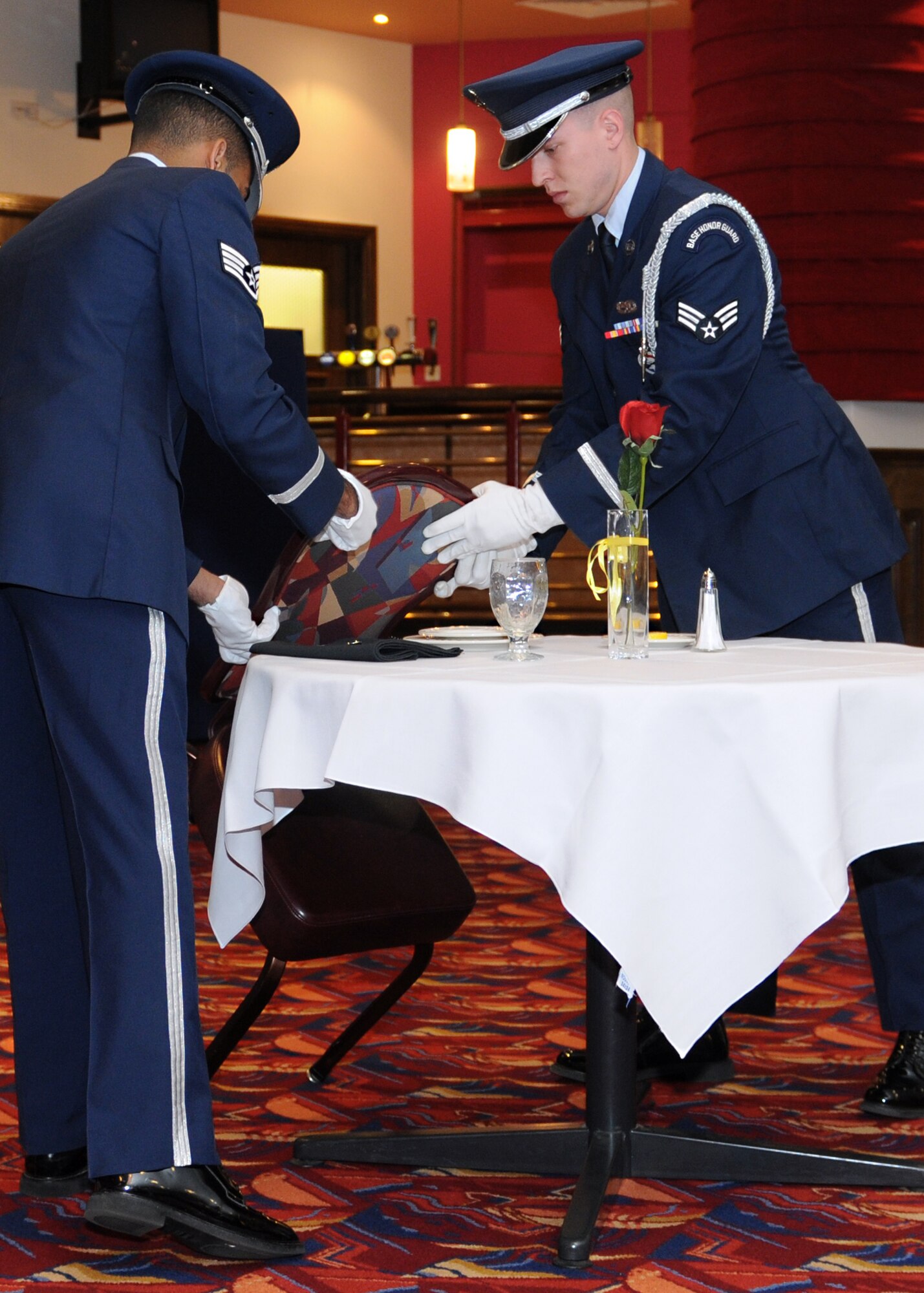 RAF MILDENHALL, England – Airmen from the RAF Mildenhall Honor Guard place an empty chair against a Prisoner of War/Missing in Action table during the POW/MIA Remembrance Luncheon here Sept. 14, 2011.  The table, set for one, symbolizes the frailty of the lone prisoners against their oppressors. (U.S. Air Force photo by Staff Sgt. Tabitha M. Lee)