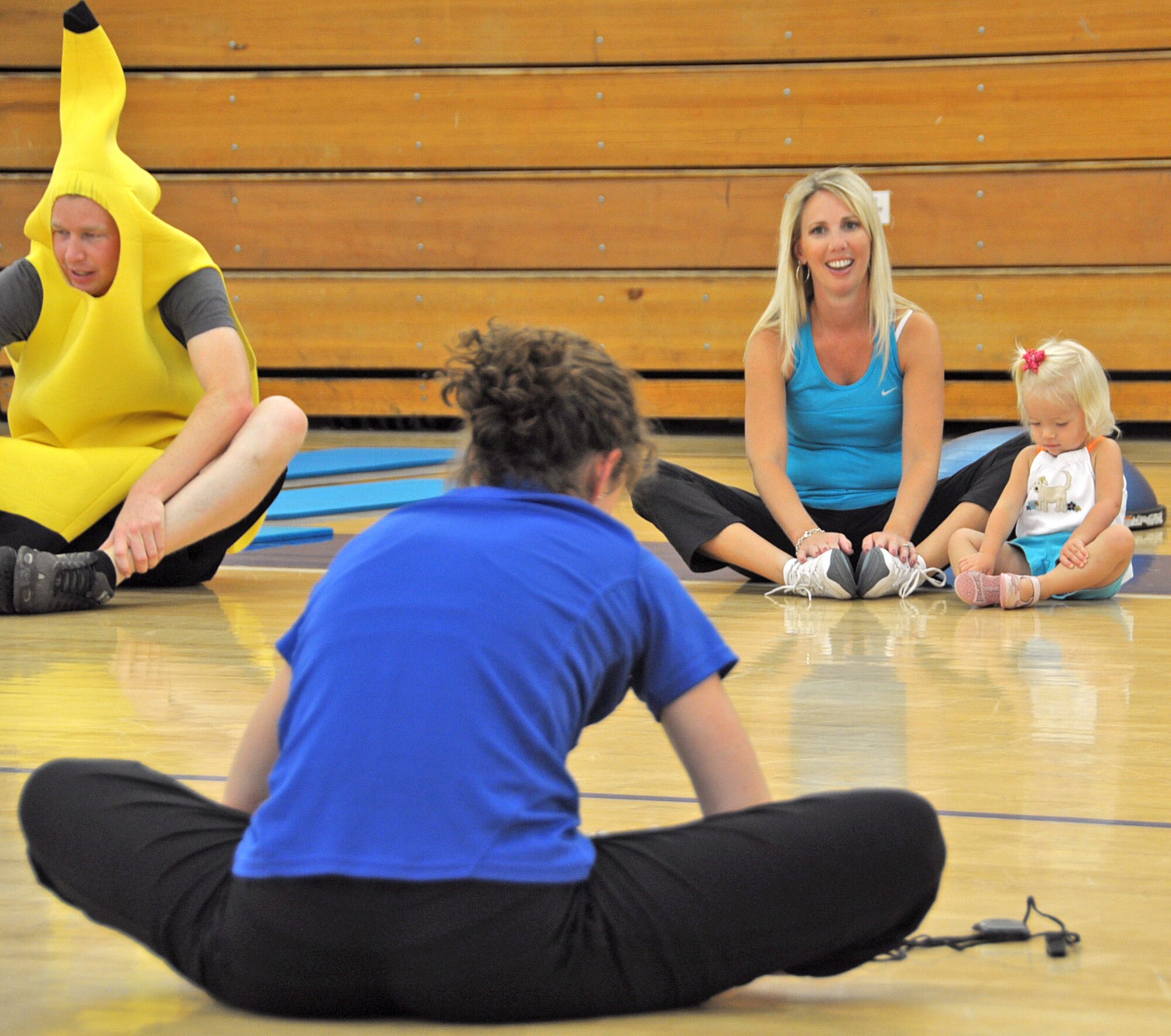 Jennifer Pearson, Health and Wellness Center coordinator, leads the 60th Maintenance Squadron and family members in a cool down stretch Sept. 9,  after demonstrating the low impact exercises for the 60th MXS Health Fair at the Fitness Center. (U.S. Air Force photo/ Airman Madelyn Ottem)