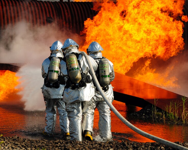 Firefighters from the Niagara Falls Air Reserve Station Fire Department exercise outside a training fuselage, to maintain proficiency at aircraft firefighting September 1, 2011 Niagara Falls, NY.  The aircraft mockup or 'burn pit' is set ablaze in different sections to properly simulate the desired training atmosphere. (U.S. Air Force photo by Staff Sgt. Joseph McKee)