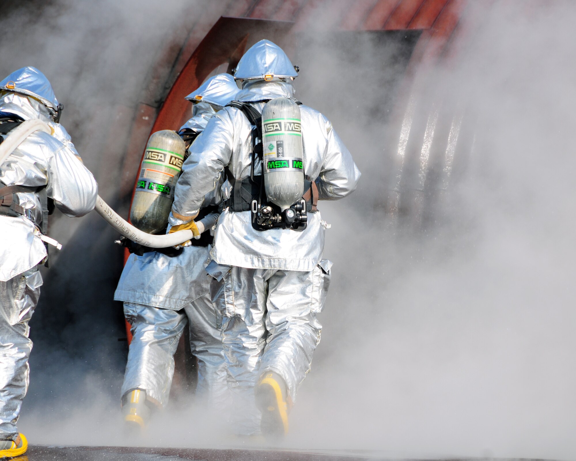Firefighters from the Niagara Falls Air Reserve Station Fire Department exercise outside a training fuselage, to maintain proficiency at aircraft firefighting September 1, 2011 Niagara Falls, NY.  The aircraft mockup or 'burn pit' is set ablaze in different sections to properly simulate the desired training atmosphere. (U.S. Air Force photo by Staff Sgt. Joseph McKee)