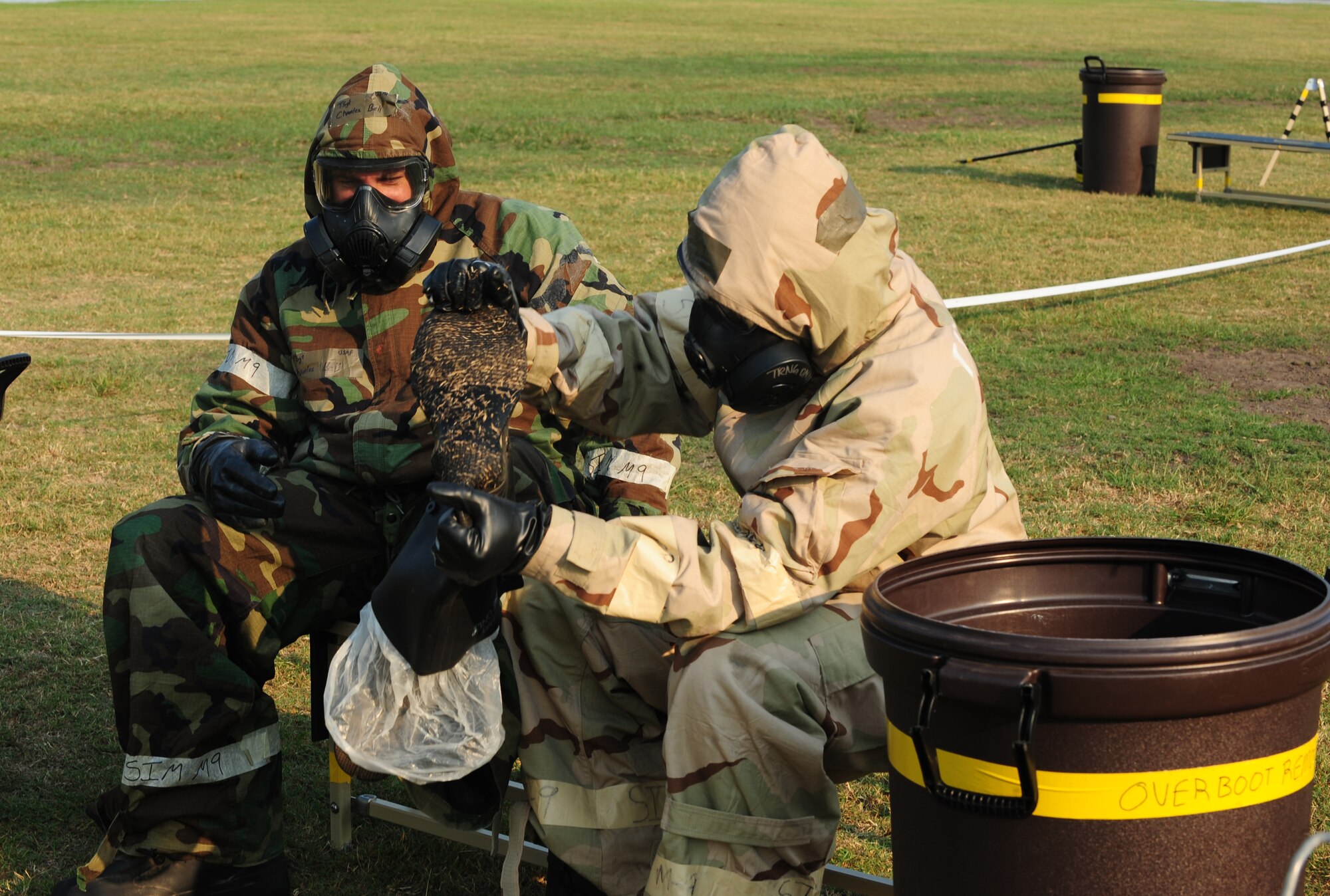 U.S. Air Force Tech. Sgt. Charles Bell, 23rd Civil Engineer Squadron water  systems and fuel  maintenance NCO in charge, and Airman 1st Class Paul Francis 23rd Wing public affairs photographer, use the buddy system to remove their protective boots during a contamination control area attendant training, at Moody Air Force Base, Ga., Sept. 14, 2011. The use of the buddy system when going through the decontamination process helps control the spread of chemical agents. (U.S. Air Force photo by Senior Airman Stephanie Mancha/Released)