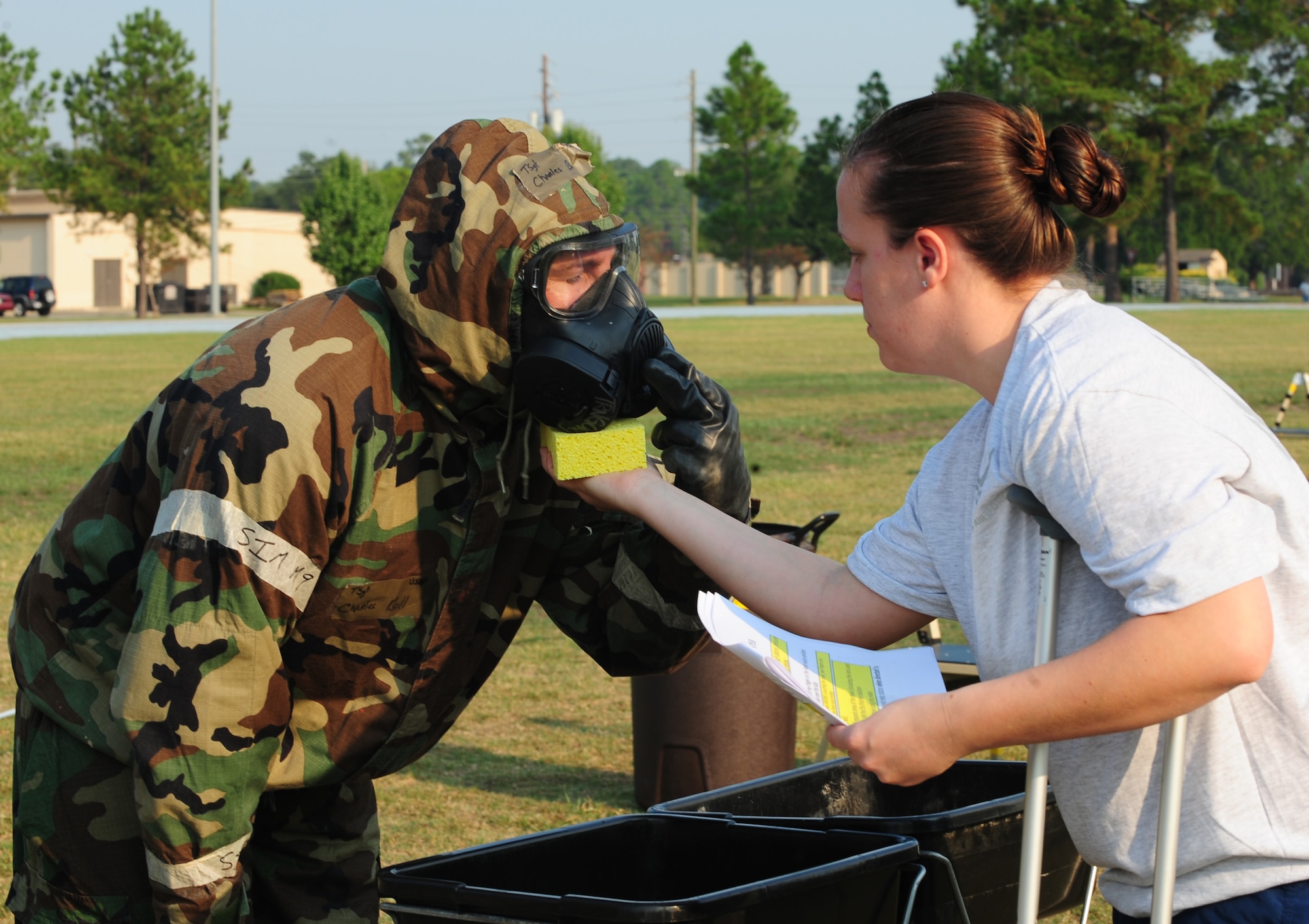 U.S. Air Force Senior Airman Laura Lee, 23rd Civil Engineer Squadron readiness and emergency management journeyman, simulates wiping the gas mask of Tech Sgt. Charles Bell, 23rd Civil Engineer Squadron water systems and fuel maintenance NCO in charge during contamination control area training, at Moody Air Force Base, Ga., Sept. 14, 2011. The decontamination process requires two wipe downs; the first with bleach and the second with water. (U.S. Air Force photo by Senior Airman Stephanie Mancha/Released)