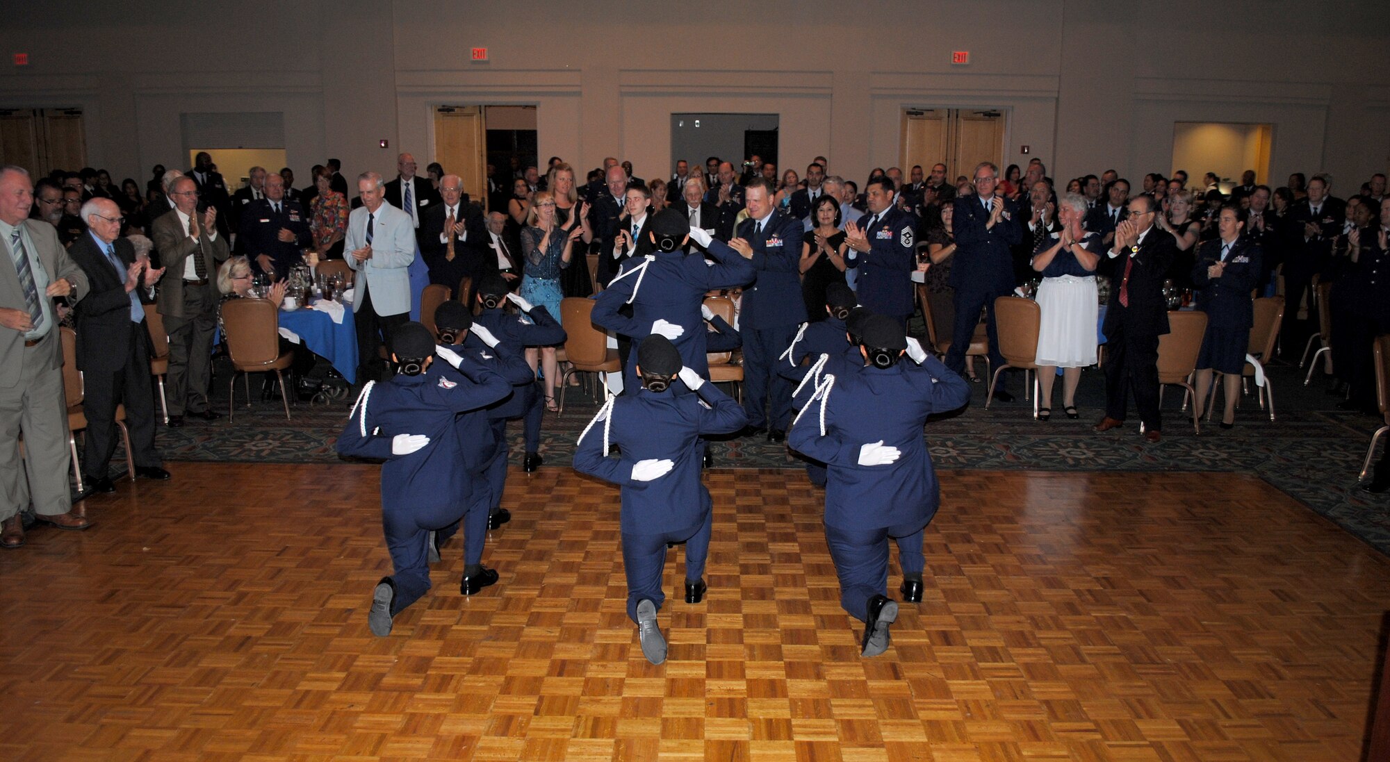 With excitement and roaring cheers guests give a standing ovation for the Brandeis High School all-female Air Force Junior ROTC unarmed precision drill team, the Blue Aces, who treated quests to a sharp-stepping drill demonstration during the 433rd Airlift Wing 60th Anniversary Dinner held Sept. 10, 2011, at the Gateway Club on Lackland Air Force Base, Texas. The local San Antonio area group said they were excited and proud to have been part of the Alamo Wing's historic celebration. (U.S. Air Force photo/Senior Airman Luis Loza Gutierrez)