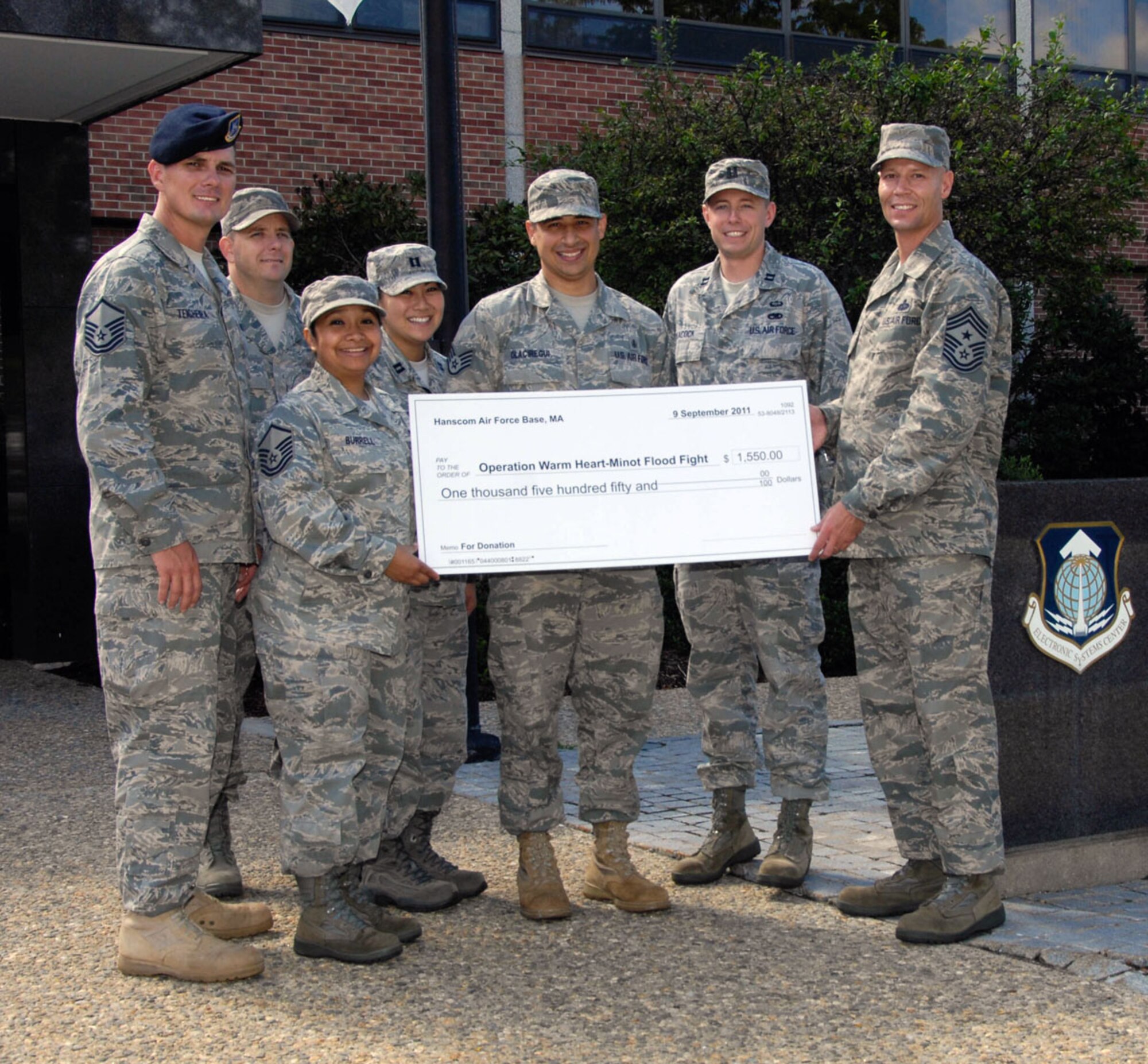 HANSCOM AIR FORCE BASE, Mass. – Members of the Company Grade Officers Council, Top 3, Air Force Sergeants Association and Patriot Enlisted Association present a check for $1,550 to Chief Master Sgt. Kevin Call (right), Electronic Systems Center command chief, to send to Operation Warm Heart for Minot flood relief efforts. The various private organizations held fundraisers to raise money that will help Airmen who were affected by the recent floods in North Dakota. (U.S. Air Force photo by Linda LaBonte Britt)