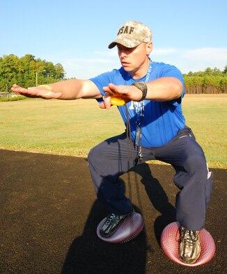 John Mikula, fit-camp instructor and exercise physiologist here demonstrates how to properly perform a balanced-squat exercise during circuit training held here Sept. 14. Training consisted of a 800-meter run, repetitious gauntlet circuit training and a 400-meter walk and sprint. (U.S. Air Force photo/Airman 1st Class Chelsea Smith)