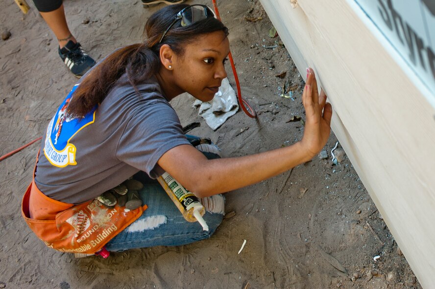 U.S. Air Force Senior Airman Shamekia Starling, 23rd Mission Support Group, applies caulk to a wall siding during a Habitat for Humanity build in Valdosta Ga., on Sept. 13, 2011.Habitat for Humanity is a non-profit organization that seeks to eliminate poverty housing and homelessness. (U.S. Air Force Photo by Staff Sgt. Joshua J. Garcia/Released)