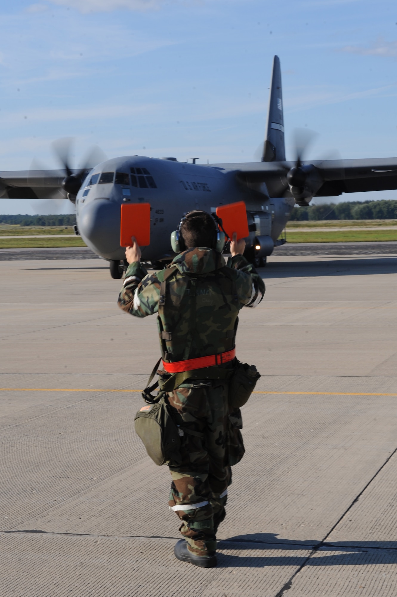 Senior Airman Andy koziek, a 19th Aircraft Maintenance Squadron crew chief, marshals a C-130J cargo plane Sept. 13, 2011, from Little Rock Air Force Base, Ark., to a designated parking ramp at Volk Field, Wis. The operational readiness exercise tested the 19th Airlift Wing's ability to deploy quickly and operate in a chemical combat environment in preparation for an operational readiness inspection in October. (U.S. Air Force photo by Tech. Sgt. Chad Chisholm) 