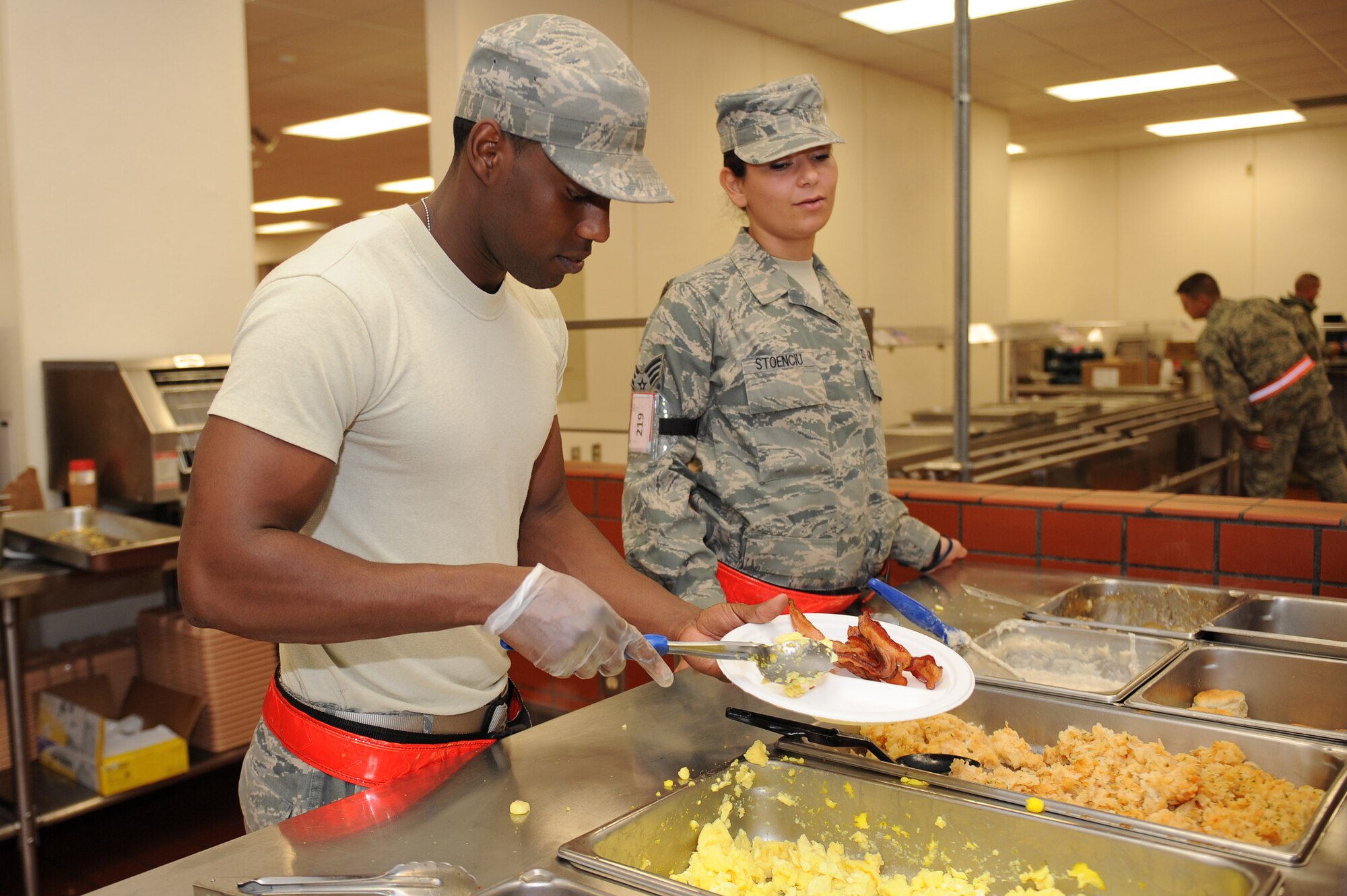 Senior Airmen Sadeek Mella and Melina Stoenciu, both 19th Force Support Squadron food service specialists, serve breakfast Sept. 14, 2011, at Volk Field, Wis. The FSS Airmen provide hot meals to the rest of the 19th Airlift Wing participating in the last operational readiness exercise before the graded operational readiness inspection in October. 