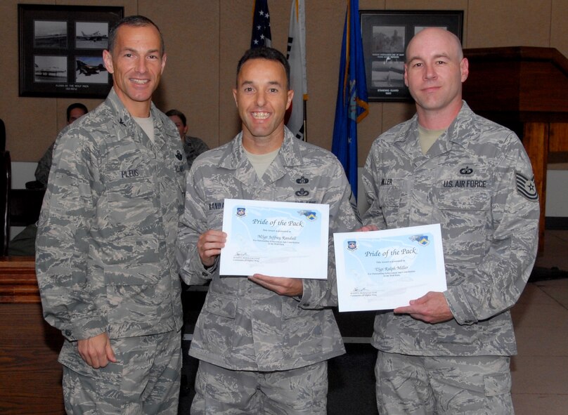 KUNSAN AIR BASE, Republic of Korea -- Col. Scott Pleus, 8th Fighter Wing commander, presents the Pride of the Pack award to Master Sgt. Jeff Randall, 8th Civil Engineer Squadron readiness and emergency management superintendent, and Tech. Sgt. Ralph P. Miller Jr., 8th Operations Support Squadron air traffic control watch supervisor, here Sept. 15. (U.S. Air Force photo/1st Lt. Trisha Eldredge)