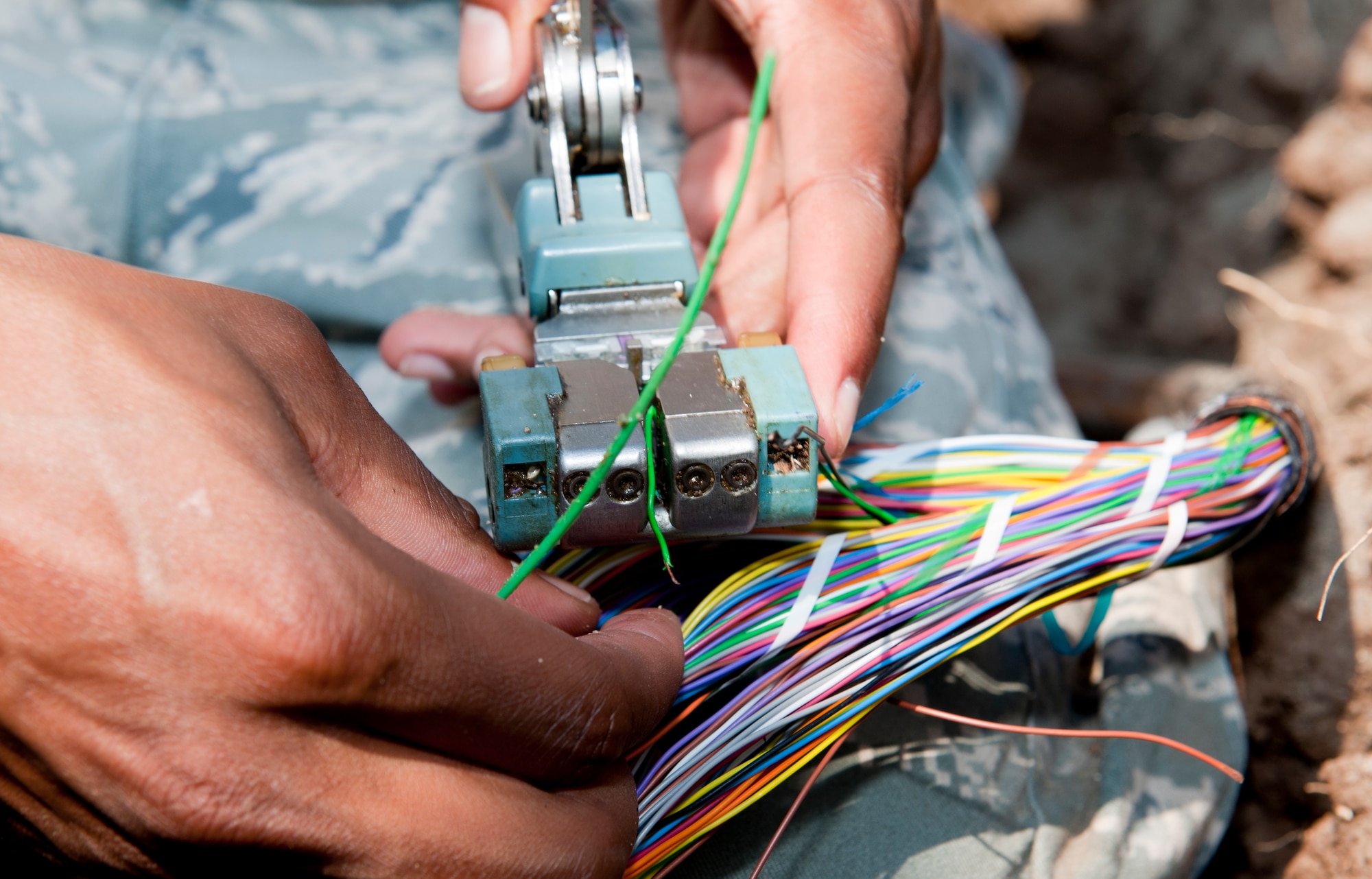 Airman 1st Class Kendall Armand, 39th Communications Squadron cable and antenna system maintenance journeyman, uses a wire splicer to connect new wire with an older line Sept. 14, 2011, at Incirlik Air Base, Turkey. The cables are spliced with new wiring when older wires are damaged or cut. (U.S. Air Force photo by Senior Airman Anthony Sanchelli/Released)