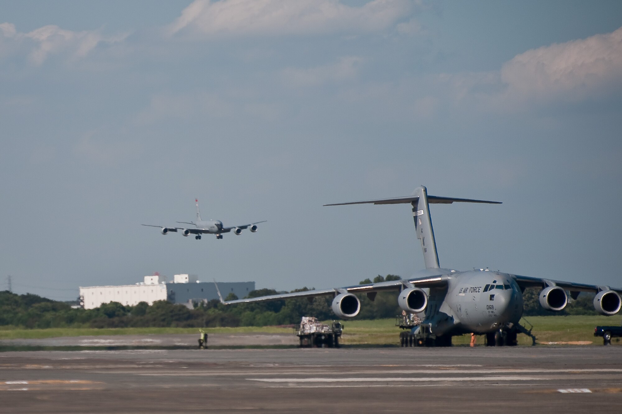 YOKOTA AIR BASE, Japan -- Airmen unload a C-17 Globemaster III as a KC-135 Stratotanker from Kadena Air Base, Japan, lands at Yokota Air Base, Japan, Sept. 15, 2011. The KC-135 and its crew have taken safe-haven at Yokota to escape an typhoon headed for Kadena. (U.S. Air Force photo/Osakabe Yasuo)