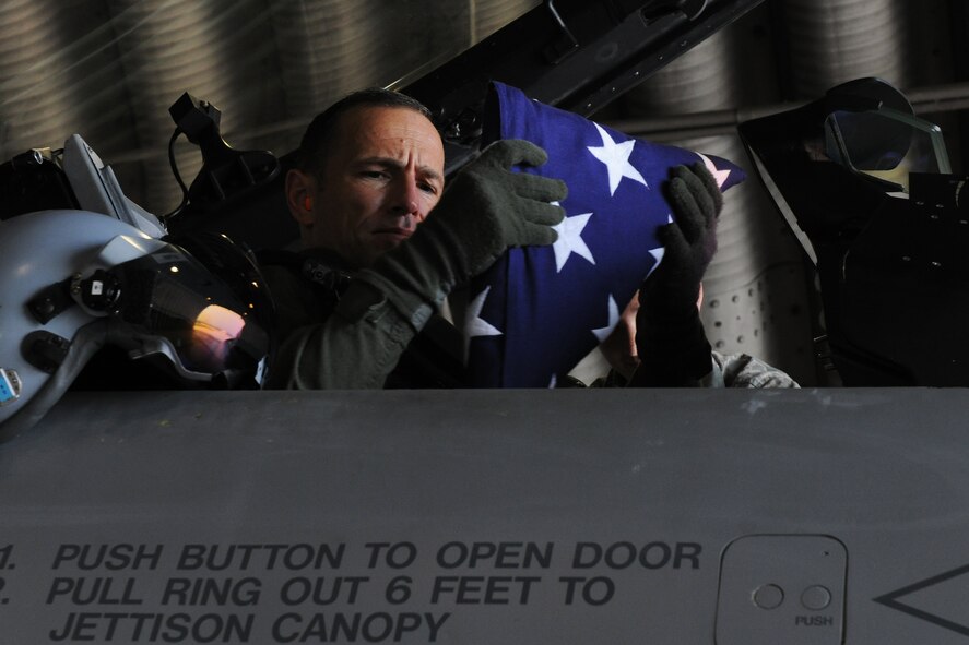 KUNSAN AIR BASE, Republic of Korea -- Col. Scott Pleus, 8th Fighter Wing commander, gets strapped in with a commemorative American flag he flew in remembrance of the 9/11 attacks here Aug. 29. Members of the Wolf Pack remembered the events of 9/11 in their own ways, but several joined up for a 10-mile ruck march and the command post played taps at the exact time each attack took place here Sept. 11. (U.S. Air Force photo/Senior Airman Brittany Y. Bateman)