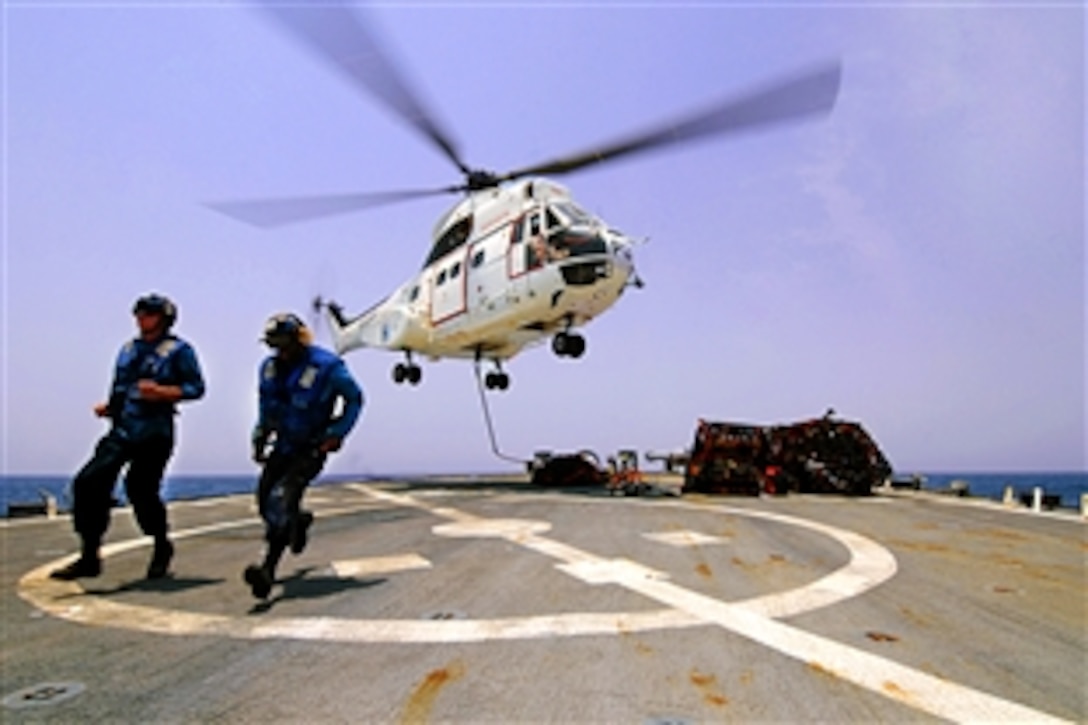 U.S. Navy Seaman Matt Binnie, left, and Seaman Recruit Jonathan Richardson, right, clear the flight deck of the USS Mitscher after attaching a cargo net to an SA-330J Puma helicopter during a vertical replenishment mission in the Gulf of Aden, Sept. 11, 2011. The Mitscher is deployed to the U.S. 5th Fleet area of responsibility conducting maritime security operations and support missions as part of Operations Enduring Freedom and New Dawn. 