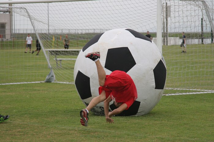 Cpl. Delshan R. Martinez, a Combat Logistics Company 36 motor vehicle operator, trips over himself as he scores a goal against Marine Aviation Logistics Squadron 12 during an earth ball game at Penny Lake field here Sept. 16. CLC-36 won a best-of-three series with a combined score of 2-0.