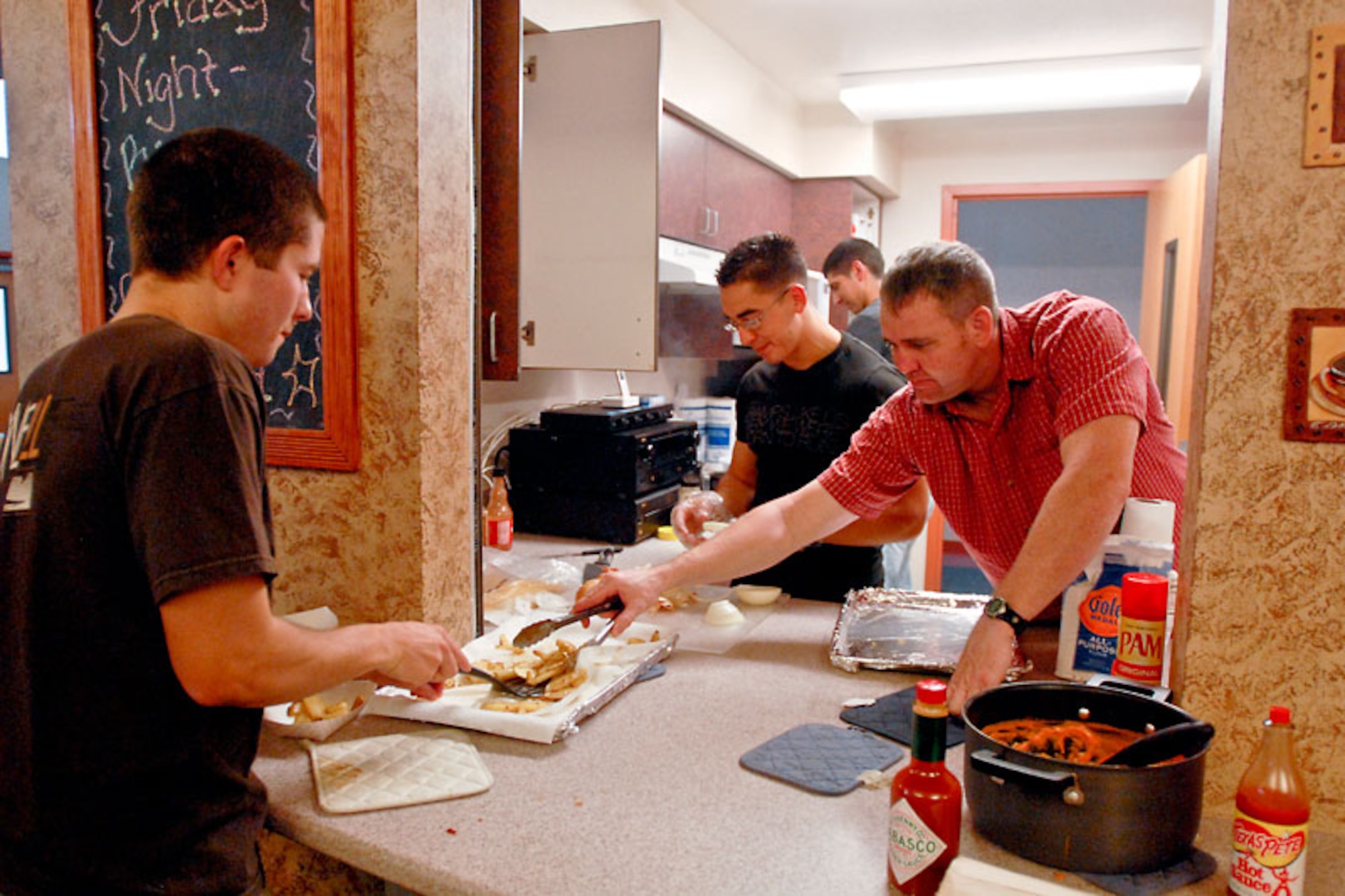 Members of the Rising Six cook for dorm residents during Friday night meal at the Wired Cafe. Friday night meal takes place at the Wired Cafe every Friday, and offers dorm residents a home-cooked meal choice, while providing an enviorment to make friends. (U.S. Air Force photo/Senior Airman Jack Sanders) 