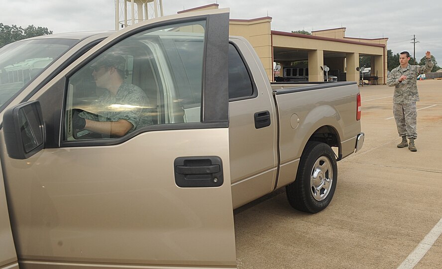 Senior Airman Jim McKibben, 2nd Logistics Readiness Squadron vehicle operator, flashes the rear lights as Staff Sgt. Daniel Conway, 2 LRS vehicle operator dispatcher, signals to him in the vehicle yard by the Vehicle Operations facility on Barksdale Air Force Base, La., Sept. 15. Before and after driving any government vehicle, a checklist is run through for safety precautions. (U.S. Air Force photo/Senior Airman Kristin High)(RELEASED)