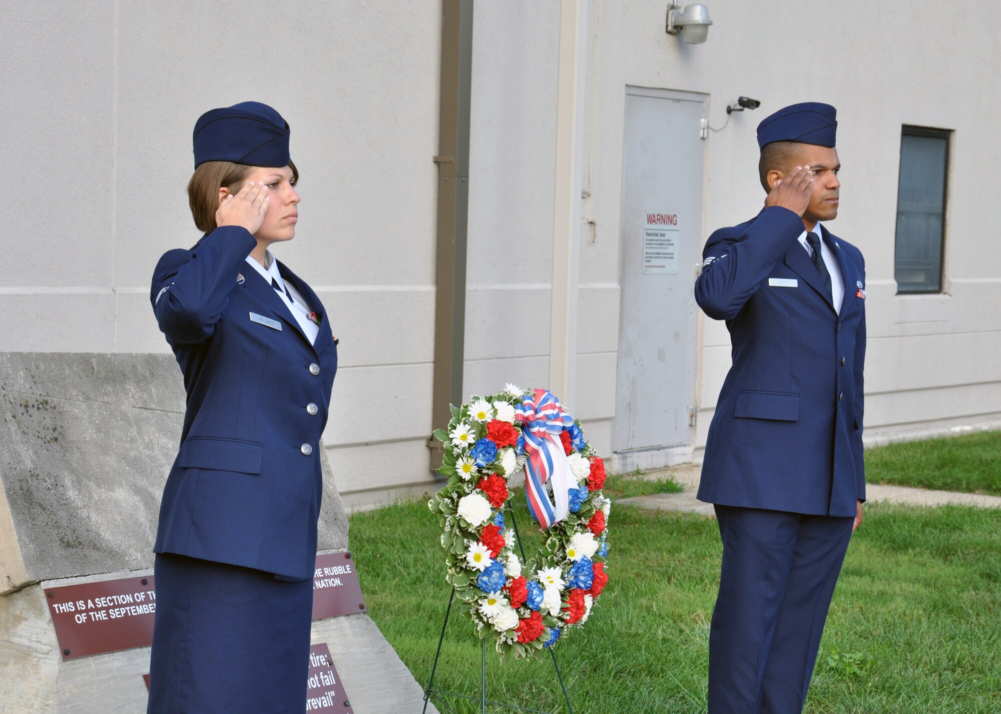 WRIGHT-PATTERSON AIR FORCE BASE, Ohio – Senior Airman Laura Wagner, 445th Airlift Wing Orderly Room, and Senior Airman Phillip Lett, 445th Aircraft Maintenance Commander Support Staff, salute during the annual 9/11 remembrance ceremony at the 445th Headquarters building Sept. 11, marking the ten year anniversary of the attacks. A wreath was placed in front of a salvaged piece of the Pentagon building that was struck by a hijacked airliner. (U.S. Air Force photo/Senior Airman Matthew Cook)