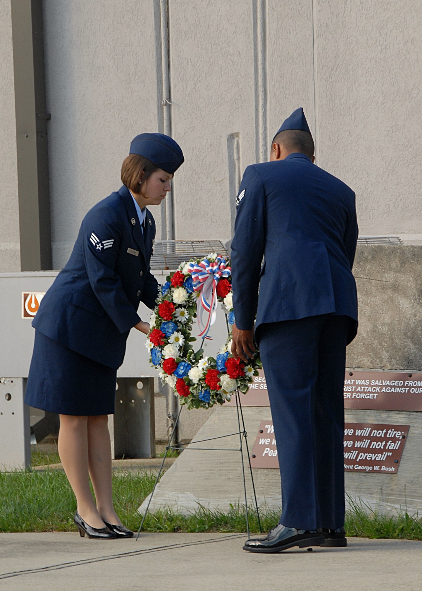 WRIGHT-PATTERSON AIR FORCE BASE, Ohio - Senior Airman Laura Wagner, 445th Airlift Wing orderly room, and Senior Airman Phillip Lett, 445th Aircraft Maintenance Squadron commander support staff, place a wreath in front of a piece of the Pentagon that was salvaged from 9/11 attacks in front of the 445th Airlift Wing Headquarters during the annual day of remembrance. (U.S. Air Force photo/Senior Airman Matthew Cook)