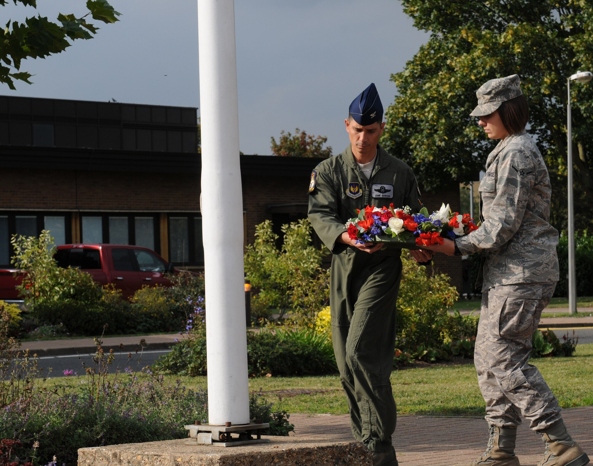ROYAL AIR FORCE LAKENHEATH, England - Col. John T. Quintas, 48th Fighter Wing commander, and Airman Amanda Tavares, 48th Operations Group intelligence analyst, place a wreath on the base of the POW/MIA flag pole during a retreat ceremony, Sept. 15, 2011. The retreat was the last event held during POW/MIA week. (U.S. Air Force photo by Airman Cory D. Payne)
