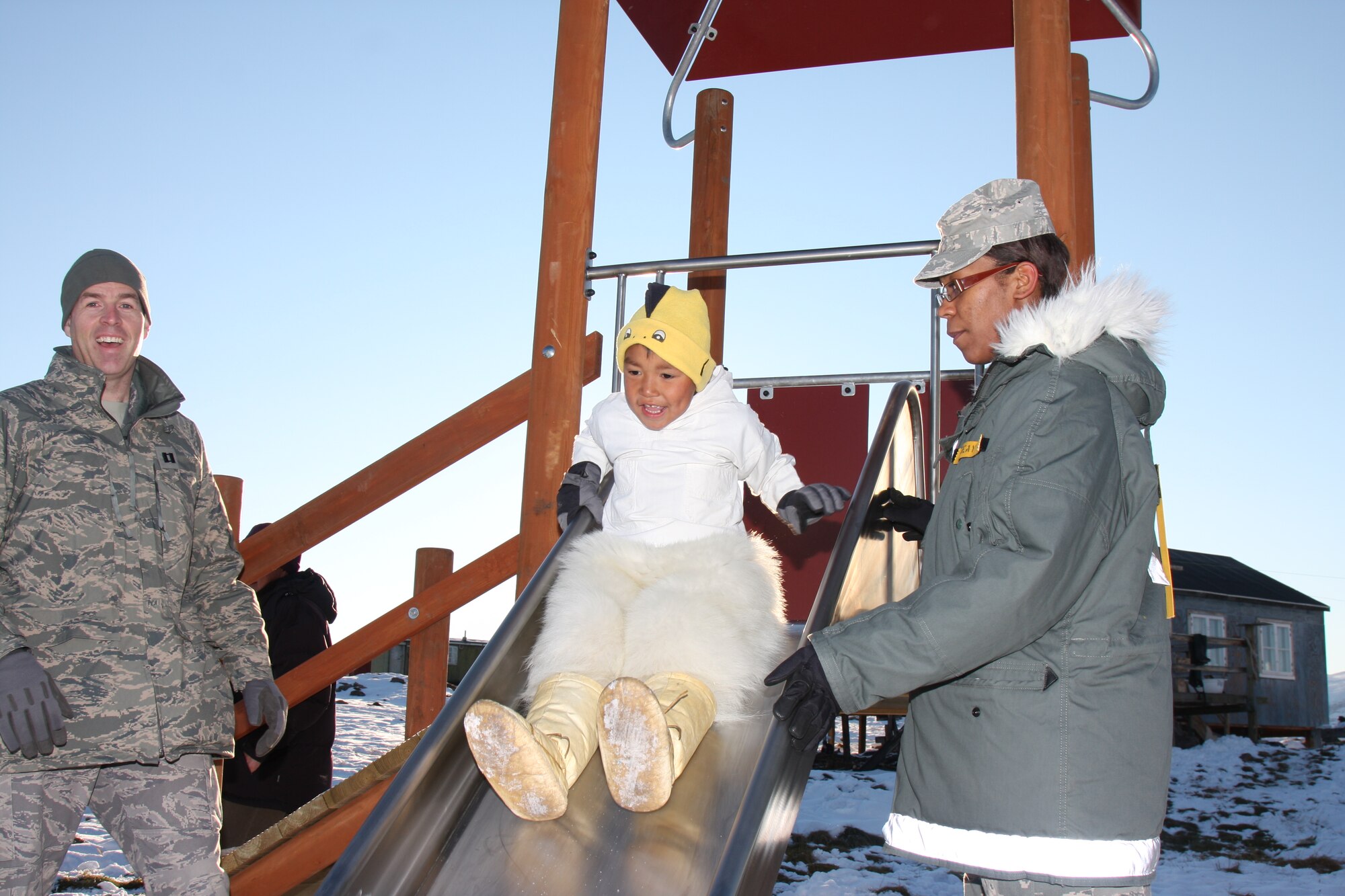 Chaplain (Capt.) Wade Matuska (left) and Staff Sgt. Lindsay Seay, 821st Air Base Group, enjoy the new playground with one of Qeqertat’s youngest residents. The playground equipment was donated by Thule Air Base personnel as part of its Operation Julemand, an annual holiday fundraiser at Thule to benefit area children. (Photo courtesy Jan Olsen)