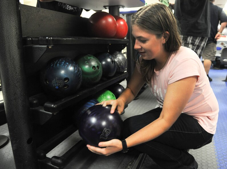 Whitnie Hendricks, member of the 23rd Equipment Maintenance Squadron bowling team, searches through bowling balls to find the right weight, at Moody Lanes, Moody Air Force Base Ga., Sept. 15, 2011. The weight of the ball affects the speed and impact that the ball will have when it hits the pins, lighter balls may roll faster but will not have as heavy an impact as an heavier ball. (U.S. Air Force photo by Airman 1st Class Paul Francis/Released)
