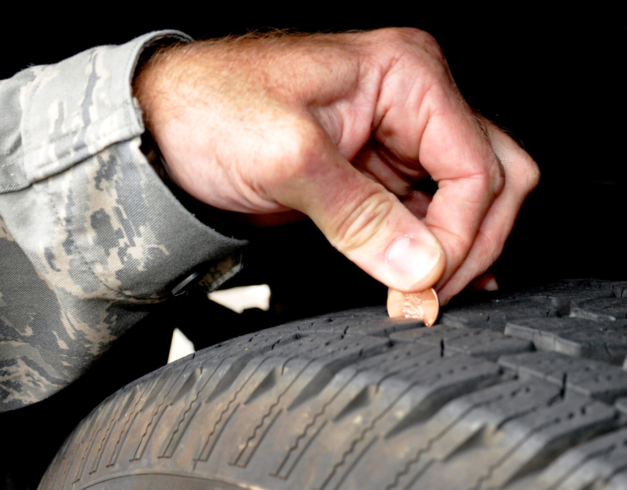 A Reservist from the 446th Airlift Wing Safety Office, McChord Field, Wash., demonstrated the coin test to check the tire tread on a vehicle, Sept. 11, 2011.  Maintaining proper tire tread levels is one of the most critical vehicle maintenance items, according to the safety office. With the fall and winter months coming up, having good tire tread helps vehicles maintain good traction on wet roads. (U.S. Air Force photo by Master Sgt. Jake Chappelle) 