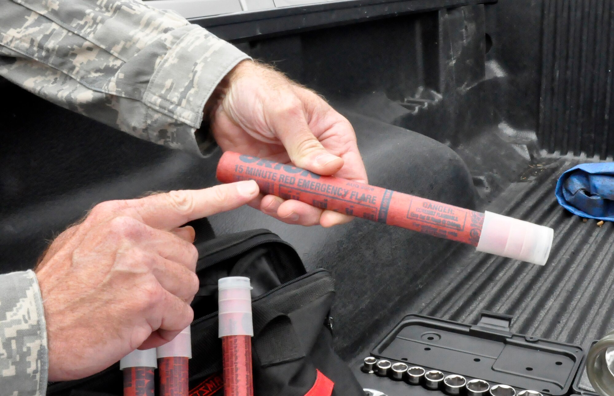A Reservist from the 446th Airlift Wing Safety Office, McChord Field, Wash., displays an example of a 15-minute roadside flare that should be included in an emergency supply kit for personal vehicles. With the fall and winter months coming up, keeping an emergency supply kit should be used in the case of, vehicle accidents, being stranded in bad weather or remote locations, vehicle breakdowns, long-distance travel, or helping others who need assistance. The safety staff recommends kits like these are stored in a backpack for easier mobility. (U.S. Air Force photo by Master Sgt. Jake Chappelle) 