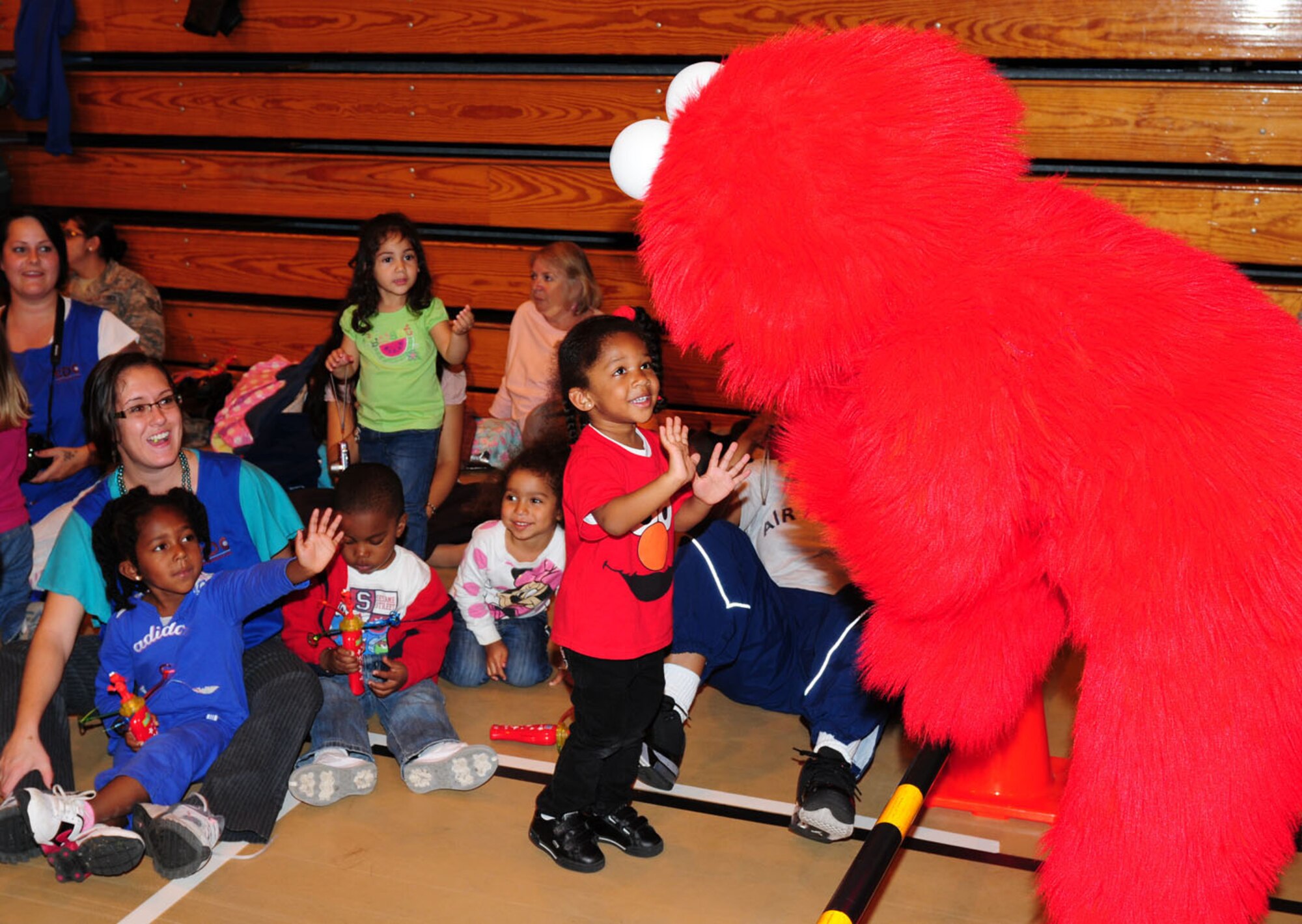 RAF MILDENHALL, England -- Alisa Buchanan, 3, daughter of Master Sgt. Nancy Buchanan, 352nd Special Operations Maintenance Squadron, waves to Elmo as he joins the audience during the Sesame Street/United Services Organization Experience for Military Families, held at the North Side Fitness Center Sept. 15, 2011. Alisa spent the event dancing to all the songs by the Sesame Street characters.More than 1,000 people attended the two performances. (U.S. Air Force photo by Karen Abeyasekere)