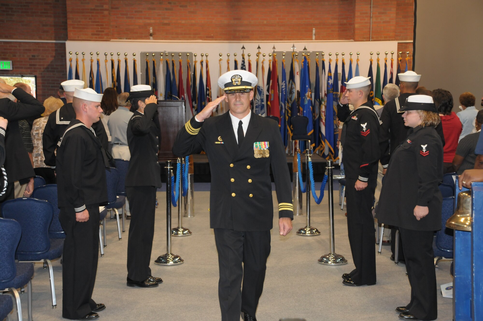 Lt. Cmdr. Chad “Coach” Tidwell, assuming commander of the Frontier Navy, salutes the side boys on the gangway during the change-of-command ceremony Sept. 10 in the Fall Hall Community Center here. (U.S. Air Force photo by Blaze Lipowski)