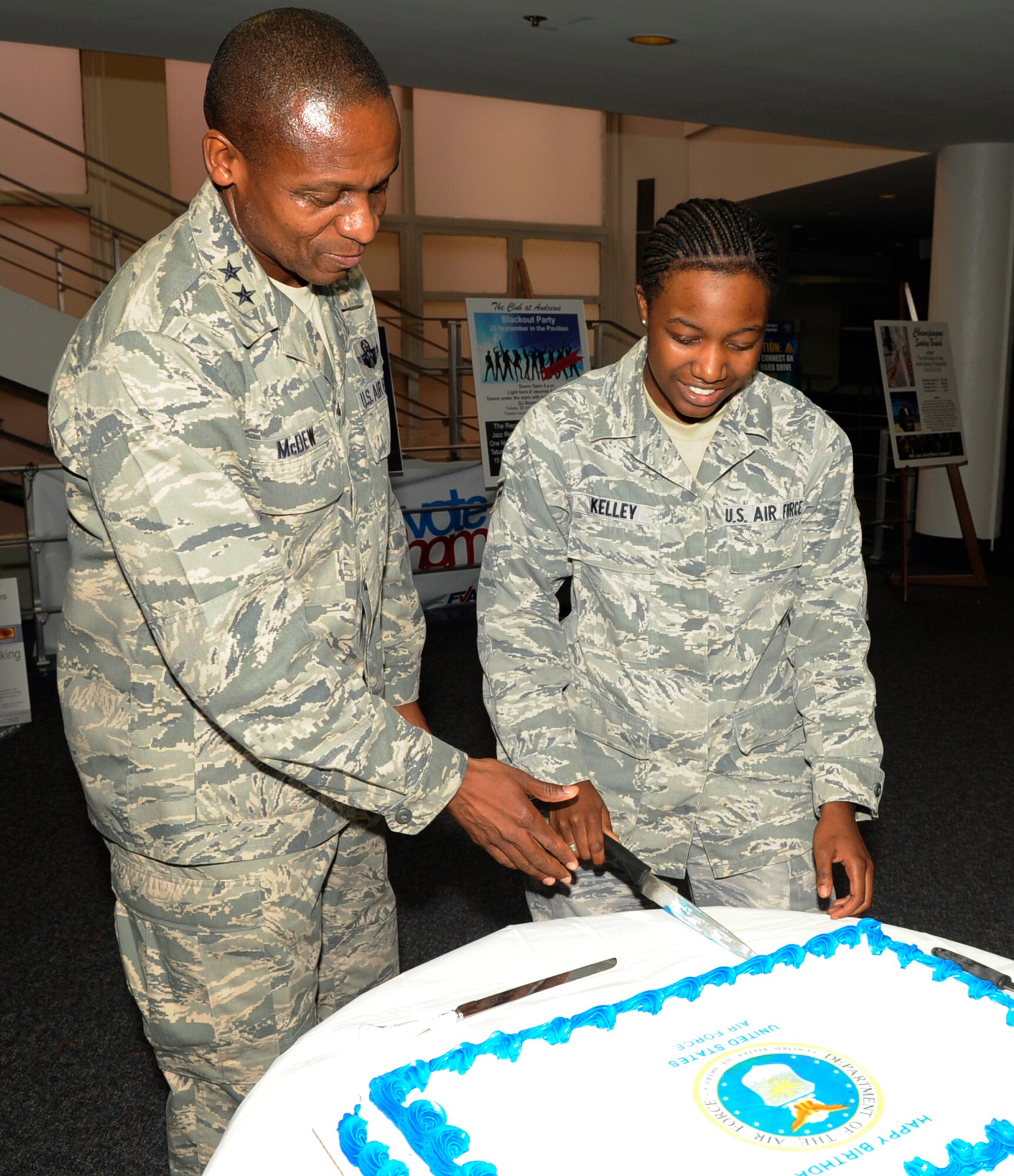 Maj. Gen. Darren W. McDew, commander of Air Force District of Washington, Washington, D.C., assists Airman 1st Class Keomi Kelley, 744th Communications Squadron, records technician, Joint Base Andrews, Md., in cutting the Air Force birthday cake Sept. 15 on Joint Base Andrews, Md. Kelly was given the opportunity to participate in the cutting of the cake because she was the youngest Airmen in attendance. (U.S. Air Force photo by Staff Sgt. Christopher Ruano)