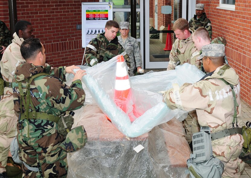 RAF MILDENHALL, England -- Students at the Ability To Survive and Operate training Sept. 14, 2011, roll up a (simulated) contaminated cover, as they learn about covering assets, contaminated waste disposal, facility personnel decontamination and mission-oriented protective posture levels. Senior Airman Nicole Browning, 100th Civil Engineer Squadron Readiness and Emergency Management, explains the correct way to remove the contaminated cover, during the training. More than 200 people participated in the training over a two-day period. (U.S. Air Force photo by Karen Abeyasekere)
