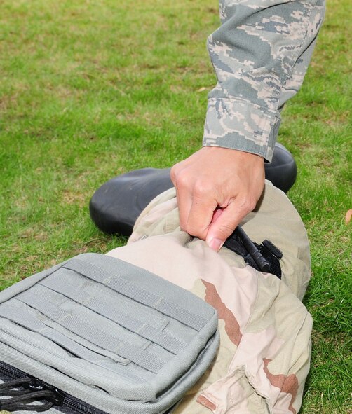 RAF MILDENHALL, England -- Tech. Sgt. Joseph Archangel, 488th Intelligence Squadron Medical Element, shows students the correct way to tighten a tourniquet, during the self-aid and buddy care portion of Ability To Survive and Operate training Sept. 13, 2011. The training involved participants wearing different stages of mission-oriented protective posture gear, and going through various skills, which also included post-attack reconnaissance, contamination control station, ATSO familiarization and weapons familiarization. (U.S. Air Force photo by Karen Abeyasekere)