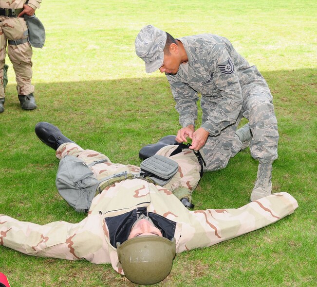 RAF MILDENHALL, England -- Tech. Sgt. Joseph Archangel, right, 488th Intelligence Squadron Medical Element, shows students how to use a tourniquet during the self-aid buddy care portion of Ability To Survive and Operate training here Sept. 13, 2011. In addition to SABC, the training involved participants wearing different stages of mission-oriented protective posture gear and going through various skills: post-attack reconnaissance, contamination control station, ATSO familiarization and weapons familiarization. More than 200 participants were trained during a two-day period. (U.S. Air Force photo by Karen Abeyasekere)
