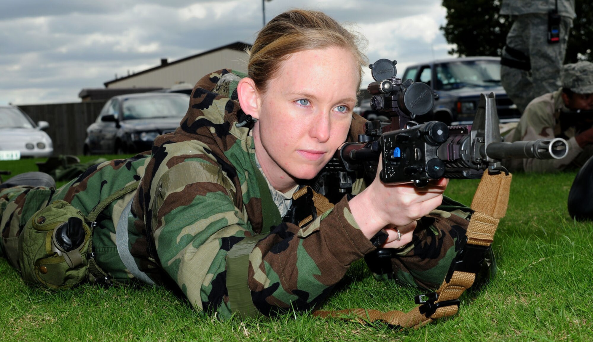 RAF MILDENHALL, England -- Staff Sgt. Mariana Babel, 100th Communications Squadron, practices M4 firing postures at the Ability To Survive and Operate rodeo Sept. 13, 2011, outside Building 680. The training involved participants wearing different stages of mission-oriented protective posture gear and going through various areas of training: self-aid and buddy care, post-attack reconnaissance, contamination control station, ATSO familiarization and weapons familiarization. During the weapons training, two members from the 100th Security Forces Squadron provided students the basic knowledge to operate weapon systems of the M4 rifle and M9 pistol. Babel uses one of the features of the M68 (close combat optic), which allows the shooter to use and engage targets with both eyes open, even when the cover is on. (U.S. Air Force photo/Karen Abeyasekere)