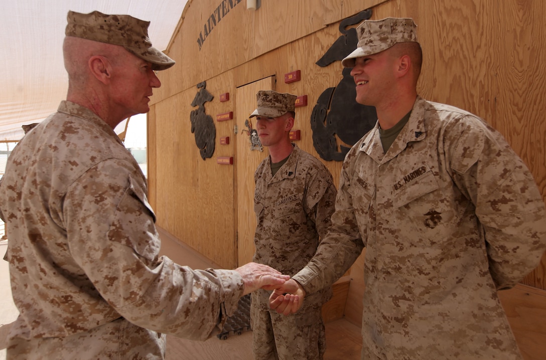 Cpl. Christopher Huber, a circuit card repair technician with 2nd Marine Logistics Group (Forward) is presented with a challenge coin by Maj. Gen. John A. Toolan, the commanding general of Regional Command Southwest, at the Intermediate Maintenance Activity lot aboard Camp Leatherneck, Afghanistan, Sept. 17. Huber and a colleague were able to save the unit more than $105,000 in equipment replacement and repair costs by fixing pieces of gear such as radios and laptop computers down to the component level vice the alternative of completely replacing the item.
