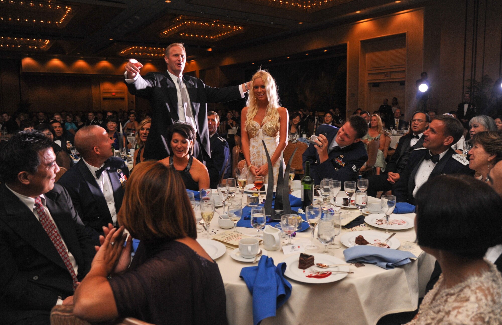 Chad Hennings, former A-10 Thunderbolt II pilot and Dallas Cowboys defensive lineman (left), sings “Happy Birthday” to Ashely Kolfage, wife of Senior Airman Brian Kolfage (right), at the 64th Annual Air Force Ball, held at the Hilton Hawaiian Village in Waikiki, Sept. 16. Brian Kolfage, a triple amputee from Operation Iraqi Freedom, was the guest of honor at the ball. (U.S. Air Force photo/Senior Airman Lauren Main)