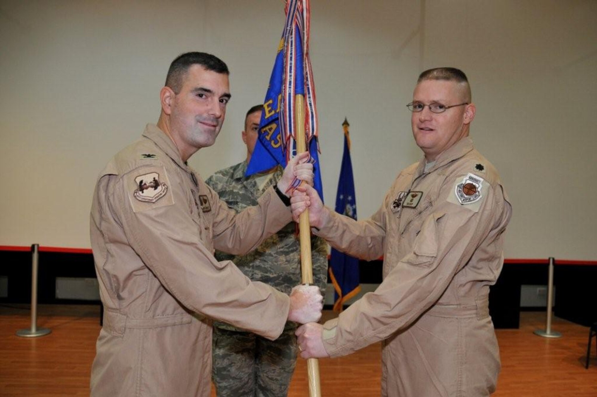 Col. Mark R. August, 386th Expeditionary Operations Group commander, left, passes the 737th Expeditionary Airlift Squadron guide-on to Lt. Col. Timothy J. Rapp during a change of command ceremony Sept. 16 at an undisclosed location in Southwest Asia. Colonel Rapp assumed command of the 737th EAS from Lt. Col. John "Tim" Julian.  (U.S. Air Force photo by Master Sgt. Carlotta Holley)