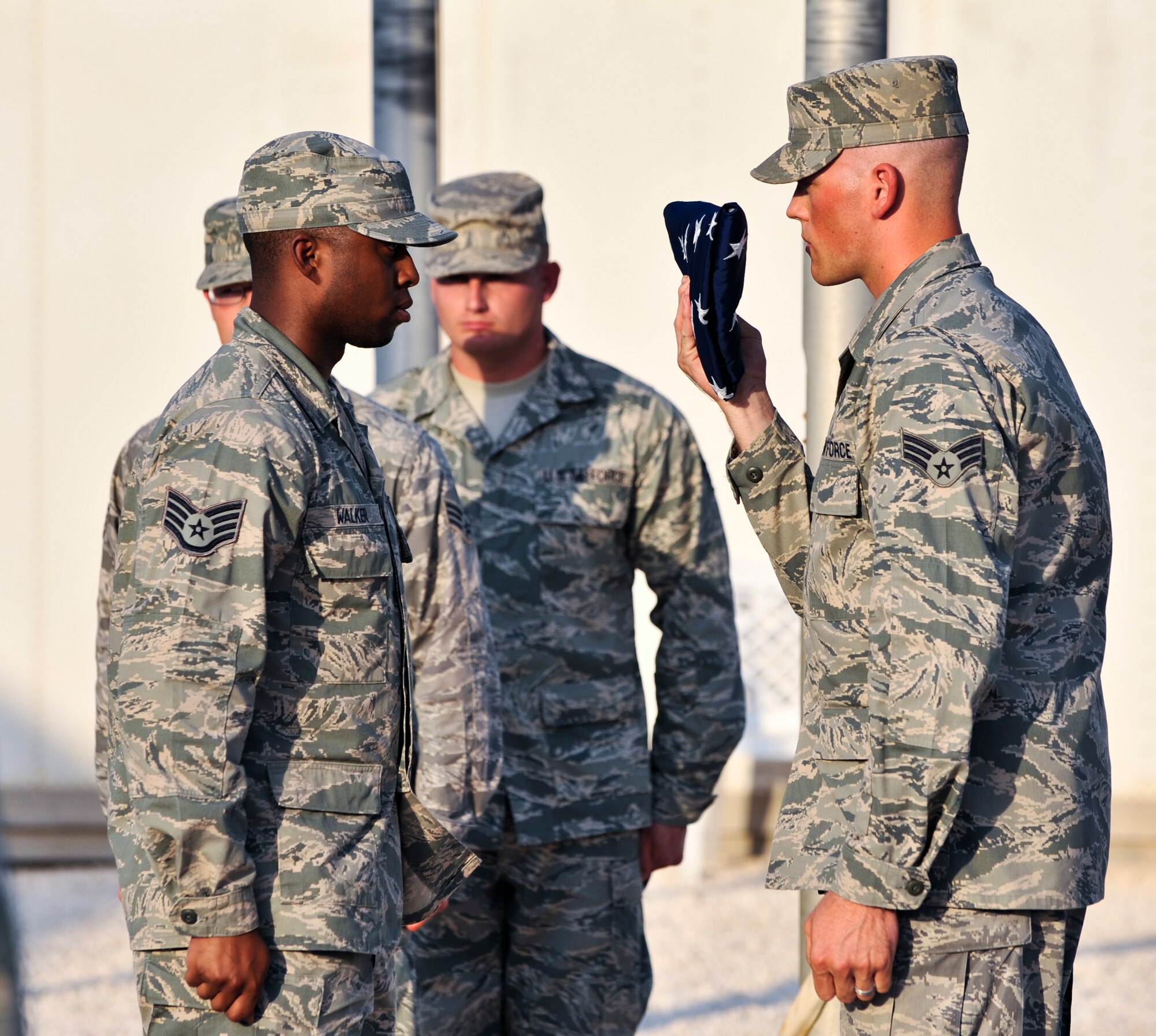 Staff Sgt. Travis Walker (left), 379th Expeditionary Communications Squadron client system technician, stands at attention as Senior Airman Justin Guilliams, 379th ECS cable antenna systems technician, prepares to hand over the American flag during a retreat ceremony, Sept. 16, 2011, at an undisclosed location in Southwest Asia. The retreat ceremony marked the final event of Cyber Awareness Week, Sept. 11-16. The week was developed to increase awareness among the base population regarding cyber threats and hackers and to educate individuals about personal responsibilities, such as risk mitigation at work and home. Walker, a native of Sacramento, Calif., is deployed from Travis Air Force Base, Calif. Guilliams, a native of Aztec, N.M., is deployed from Kapaun Air Station, Germany. (U.S. Air Force photo/Senior Airman Paul Labbe)