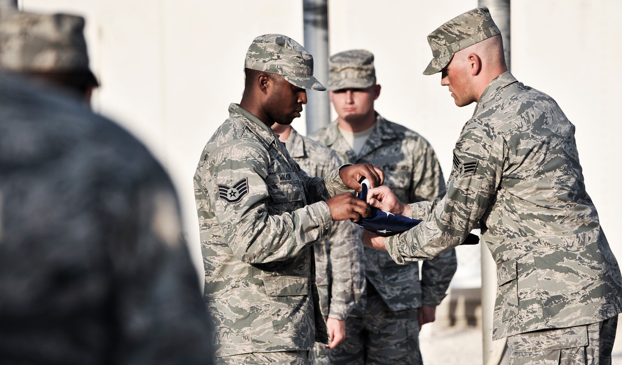 Staff Sgt. Travis Walker (left), 379th Expeditionary Communications Squadron client system technician, assists Senior Airman Justin Guilliams, 379th ECS cable antenna systems technician, as they fold the American flag, Sept. 16, 2011, during a retreat ceremony at an undisclosed location in Southwest Asia. The retreat marked the final event of Cyber Awareness Week, Sept. 11-16. The week was developed to increase awareness among the base population regarding cyber threats and hackers and to educate individuals about personal responsibilities, such as risk mitigation at work and home. Walker, a native of Sacramento, Calif., is deployed from Travis Air Force Base, Calif. Guilliams, a native of Aztec, N.M., is deployed from Kapaun Air Station, Germany. (U.S. Air Force photo/Senior Airman Paul Labbe)