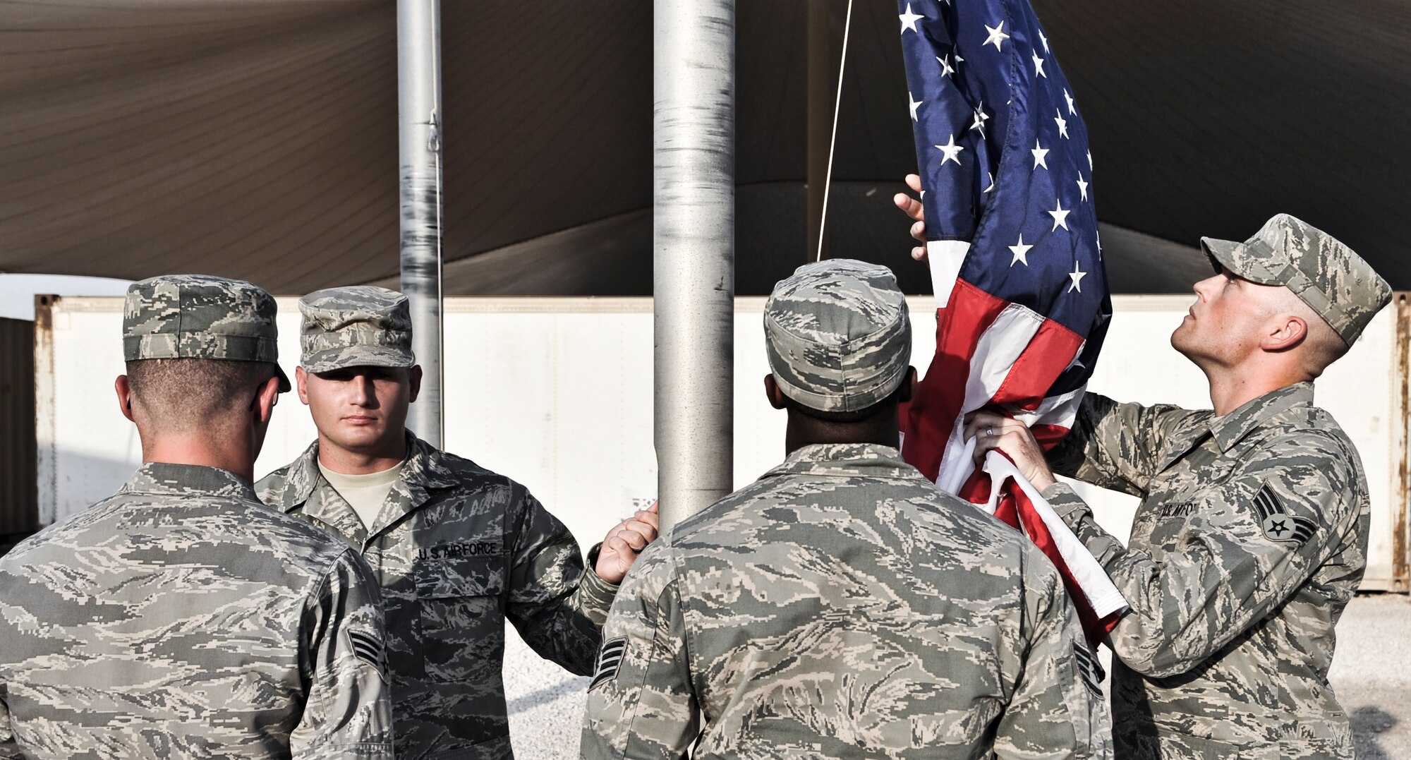 Senior Airman Justin Guilliams, 379th Expeditionary Communications Squadron cable antenna systems technician, retrieves the American flag as it is lowered during a retreat ceremony, Sept. 16, 2011, at an undisclosed location in Southwest Asia. The retreat marked the final event of Cyber Awareness Week, Sept. 11-16. The week was developed to increase awareness among the base population regarding cyber threats and hackers and to educate individuals about personal responsibilities, such as risk mitigation at work and home. Guilliams, a native of Aztec, N.M., is deployed from Kapaun Air Station, Germany. (U.S. Air Force photo/Senior Airman Paul Labbe)