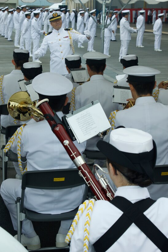 The Japanese Maritime Self-Defense Force Fleet Air Wing 31 band composer guides the JMSDF FAW-31 band through a marching song as JMSDF sailors participating in the opening ceremony of the JMSDF Iwakuni Air Base Festival here Sunday. The JMSDF Iwakuni Festival, celebrated annually in the fall, commemorated the 38th anniversary of the force’s command aboard the station. The festival helped familiarize Japanese off-base residents with JMSDF units and activities, and strengthen exchange and support through the community.