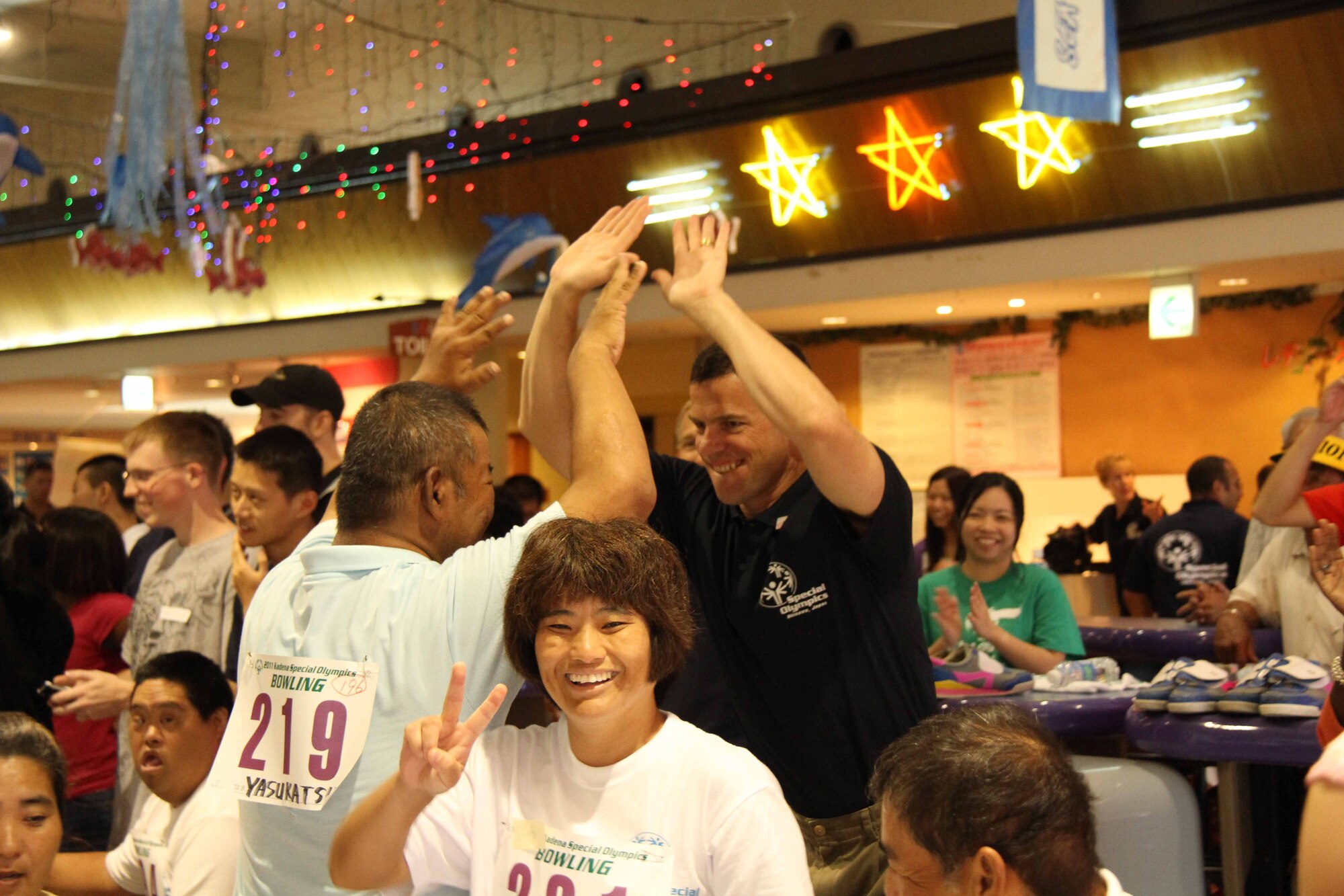 Brig. Gen. Matt Molloy, 18th Wing commander, gives high fives to Yasukatsu Fukuhara after he scores a strike in the fifth frame during the 12th annual Kadena Special Olympics Bowling Tournament at Seaside Bowl Mihama in Chatan Town, Japan, Sept. 17. Fukuhara works at the Kuwanomi (mulberries) special needs workshop in Uruma City. (U.S. Army photo/Chip Steitz)