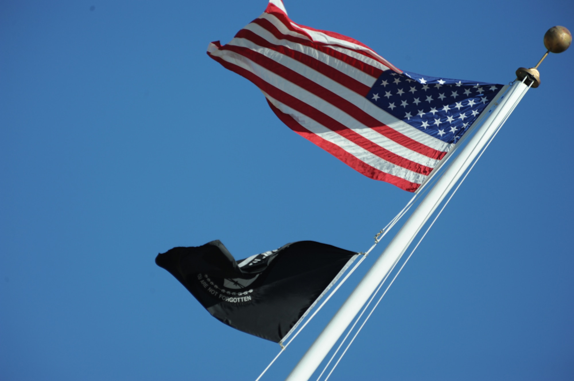 The National League of Families' POW/MIA flag blows in the wind while below the U.S. Flag while more than 200 past and present military members gathered with civilians to celebrate National POW/MIA Recognition Day with the Joint POW/MIA Accounting Command (JPAC) at the National Memorial Cemetery of the Pacific (Punchbowl) in Honolulu, Hawaii on Sept. 16. The third Friday of Sept. has served as the National POW/MIA Recognition Day since 1986 and honors and recognizes the sacrifices of those Americans who have been prisoners of war and to remind the Nation of those individuals that are still missing.  JPAC is responsible for the recovery of missing Americans from past conflicts and travels all around the world in search of those individuals in order to bring full accountability to their families and the American people.  (DoD photo/Master Sgt. Cohen A. Young)
